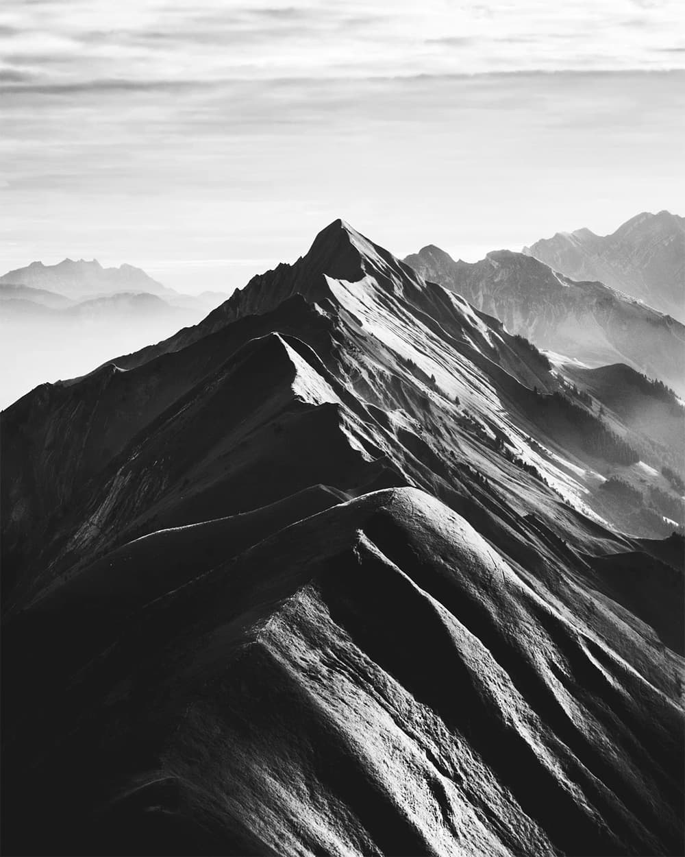Black-and-white mountain peak rising above the clouds
